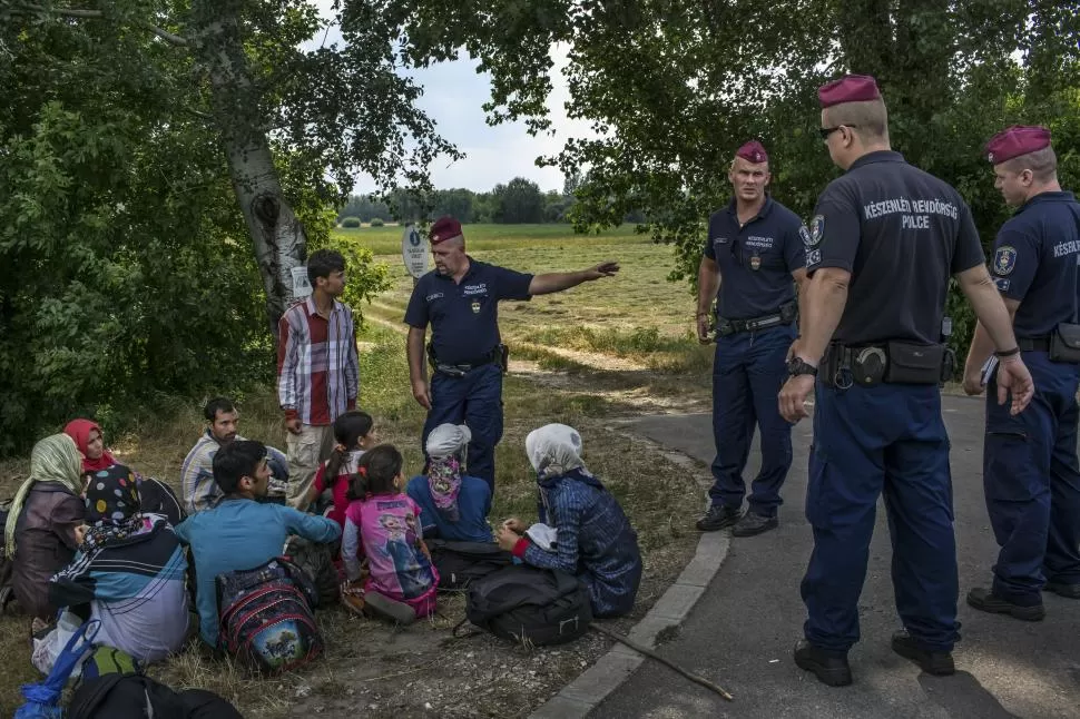 EN LA FRONTERA. Refugiados afganos son detenidos por la policía húngara, poco después de cruzar desde Serbia. foto de Mauricio Lima / the new york times