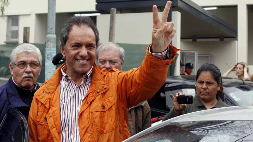 LA V. Scioli saluda con el tradicional gesto peronista, al salir de votar. REUTERS