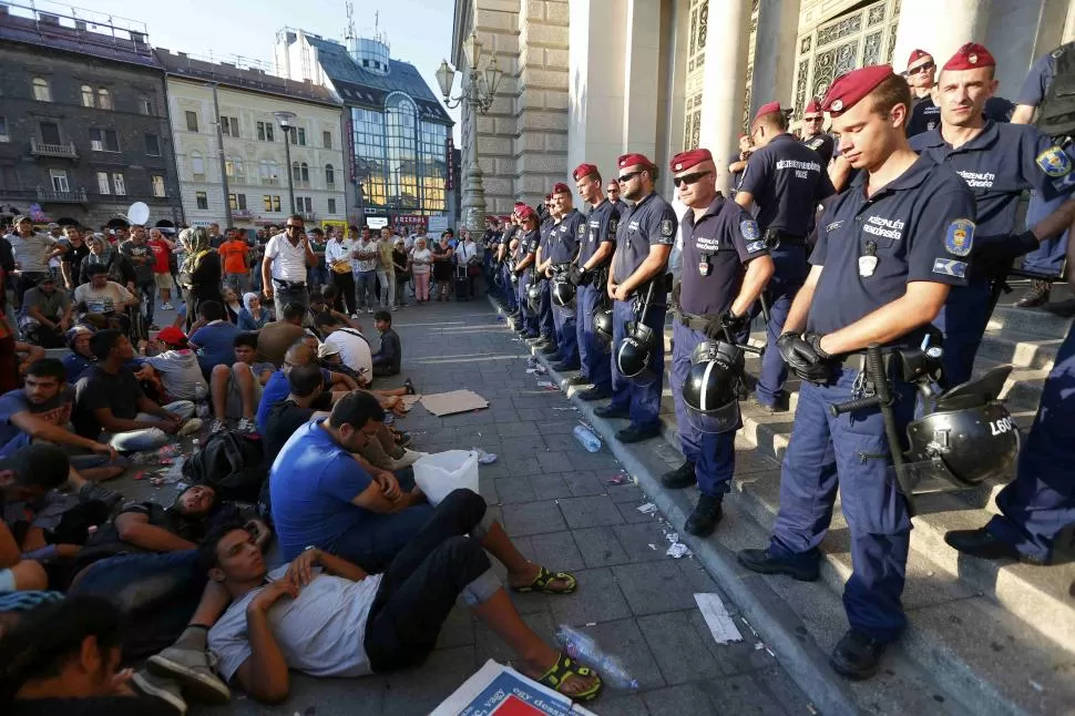 LA SENTADA DE PROTESTA. Policías húngaros impiden el acceso de cientos de inmigrantes a la estación de ferrocarril de Budapest-Este. reuters 