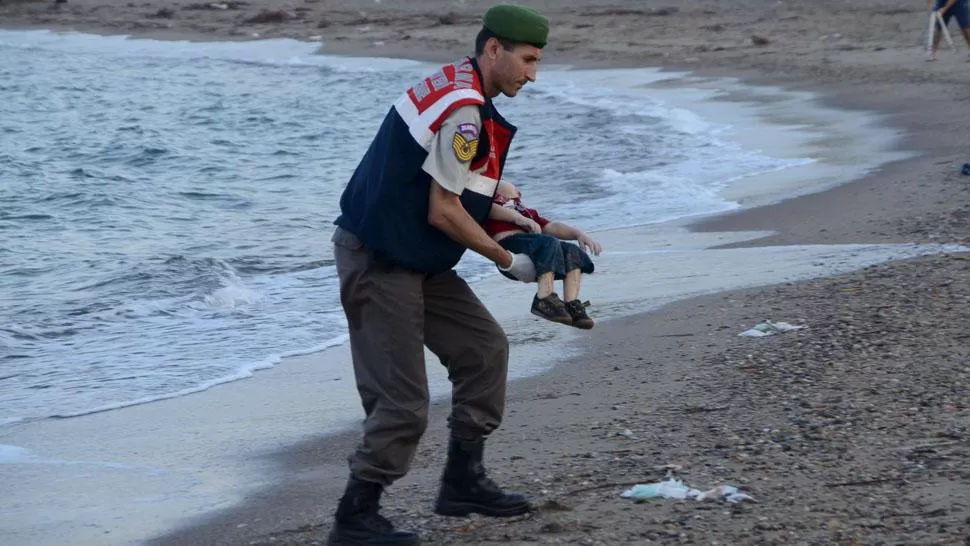 TAREA MACABRA. Un gendarme turco recoge el cuerpo niño de una playa de Bodrum. REUTERS
