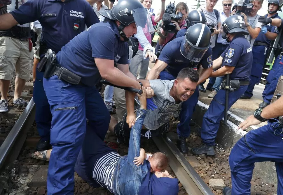 LOS INCIDENTES. La policía húngara retira a inmigrantes de las vías del tren. 