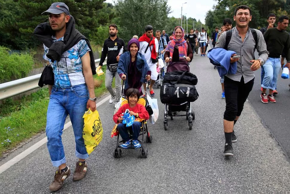 CANSADOS PERO FELICES. Grupos de inmigrantes caminan hacia Austria, luego de que el país les abriera la frontera. REUTERS