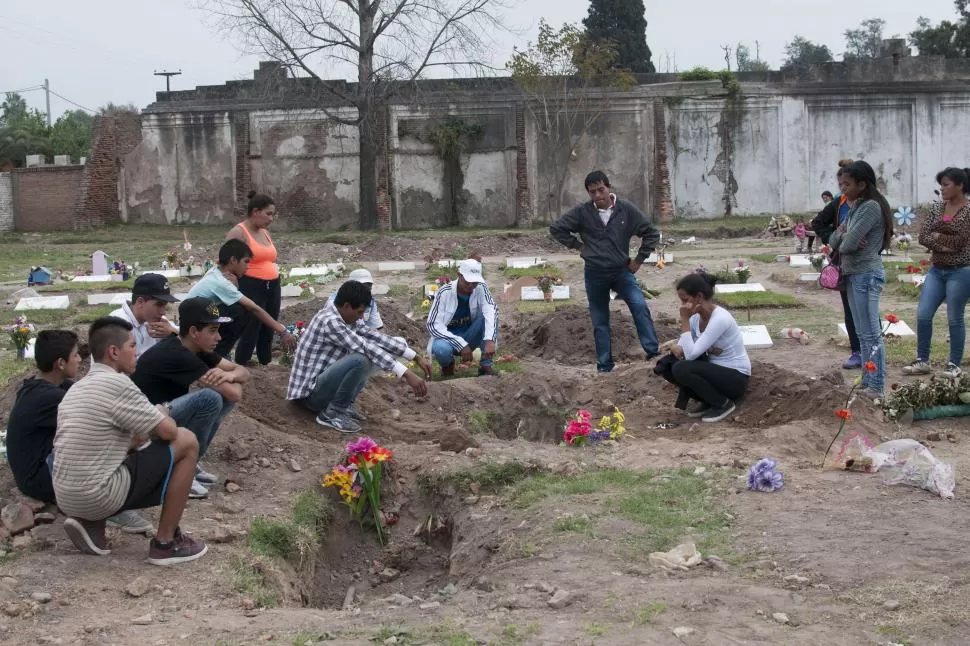 - DOLIDOS. El entierro terminó, pero sus amigos no se mueven de allí, de donde Horacio no saldrá más. LA GACETA / FOTO DE INÉS QUINTEROS ORIO. 
