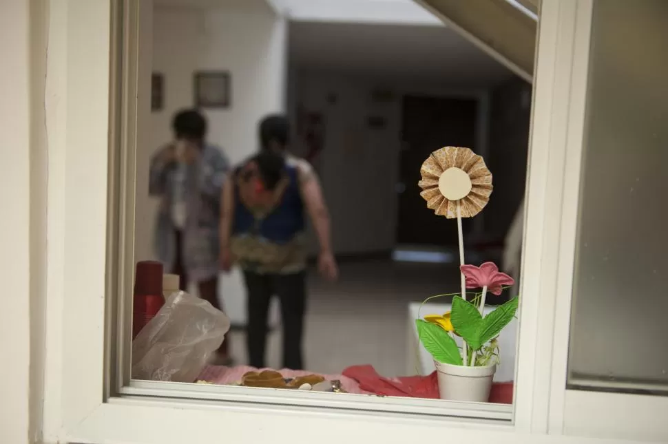 LOS PRIMEROS ADORNOS. Flores de papel decoran la ventana de uno de los dormitorios; atrás, dos pacientes charlan en el hall de la casa. LA GACETA / FOTOS DE FLORENCIA ZURITA.