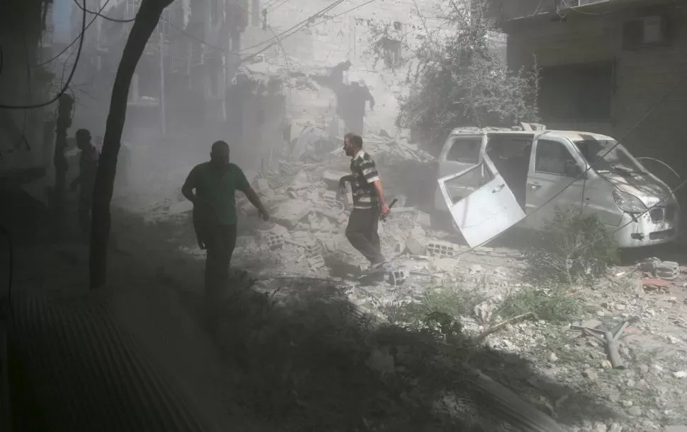 DESTRUCCIÓN. Pobladores de la ciudad de Douma, al este de Damasco, caminan entre los escombros y los daños producidos por un ataque aéreo. reuters