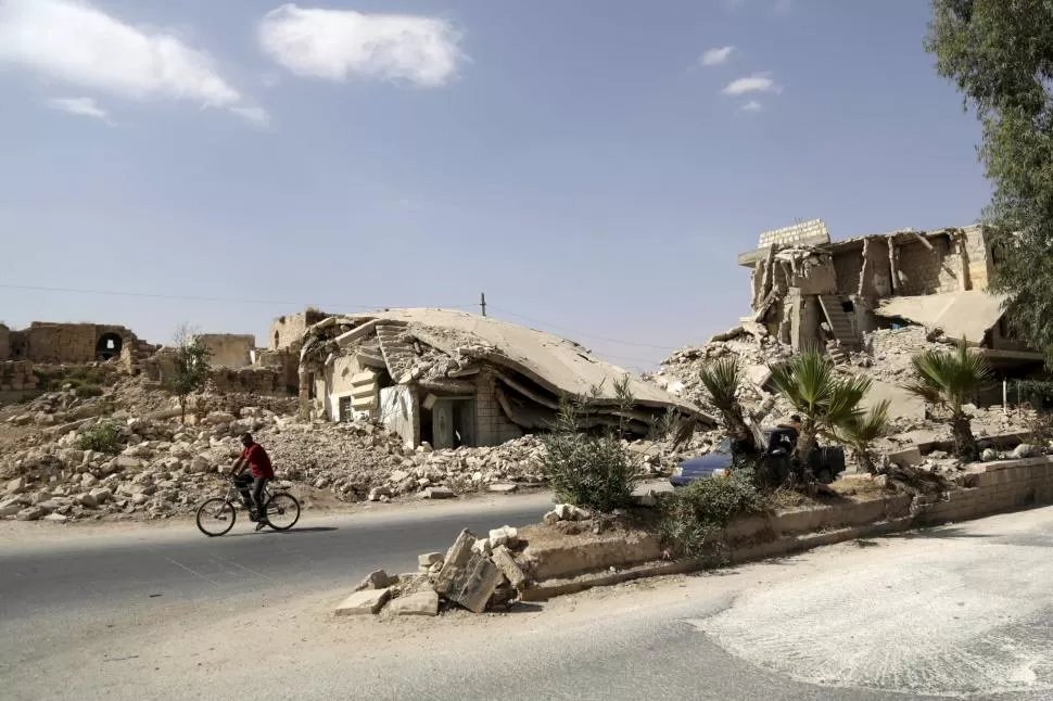 DAÑOS. Un hombre se desplaza en bicicleta por una de las calles de la ciudad de Maaret al-Naamán, en Idlib. Las consecuencias de los ataques aéreos y la lucha entre el Ejército y los rebeldes son dramáticamente evidentes. reuters 