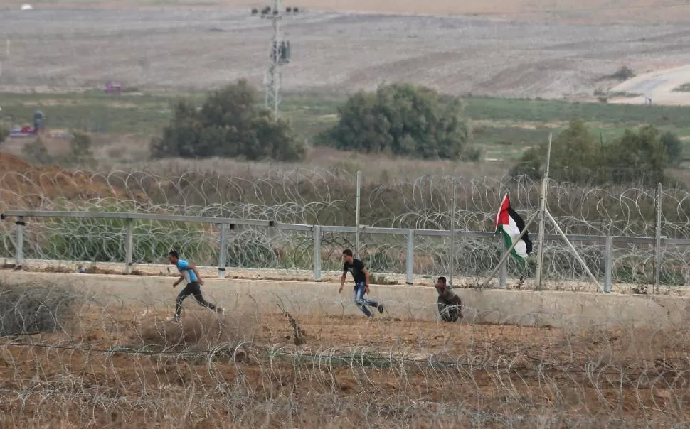 FRANJA DE GAZA. Jóvenes palestinos huyen de la policía israelí, entre la alambrada que divide los territorios. Los enfrentamientos se mantienen. reuters