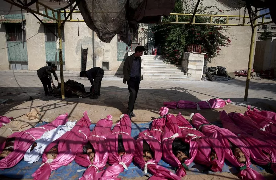 DAMASCO. Vecinos del barrio de Douma identifican los cuerpos reunidos en un centro de defensa civil. Hubo unos 40 muertos al caer misiles en el mercado.  reuters