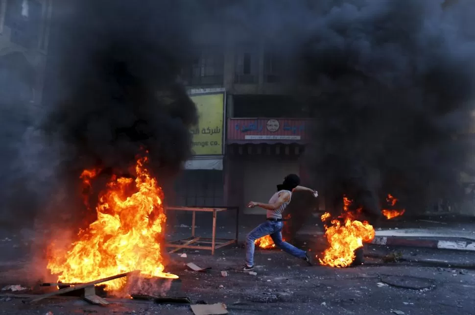 EN HEBRÓN. Un palestino lanza piedras, entre las barricadas que levantaron. reuters