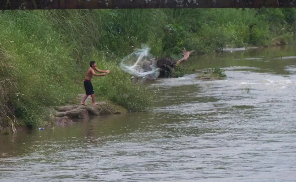 SIN PONERSE COLORADO. Un adolescente arroja una red en el río Medina. Cada vez son menos los pescadores que utilizan cañas.FOTOS  / LA GACETA - OSVALDO RIPOLL -  GENTILEZA PEDRO CÓRDOBA.