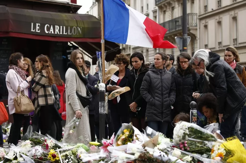 UN VIERNES 13 QUE SERÁ HISTÓRICO Y DOLOROSO. Los franceses dejan ofrendas florales frente al bar Le Carrilon, uno de los escenarios atacados por los terroristas en París. 