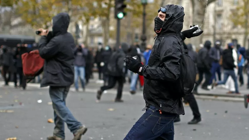 VIOLENCIA. Un manifestante arroja un objeto contra la Policía en una calle de París. FOTO DE REUTERS