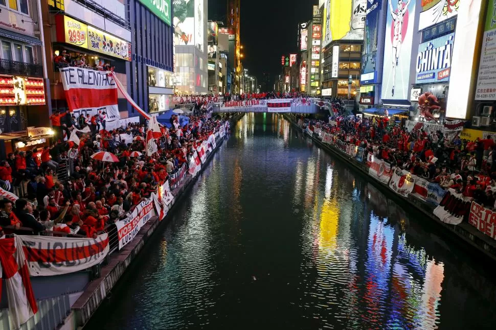 FIESTA EN JAPÓN. Miles de hinchas de River alentaron al equipo antes del encuentro de hoy con un banderazo junto a un canal de Tokio. Nadie llevó tantos hinchas a Japón como el “millonario”.  reuters