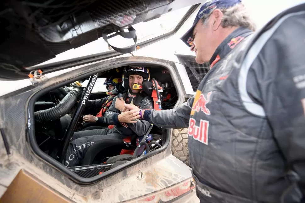 COMPAÑEROS. Peterhansel, a bordo del Peugeot, recibe el saludo de Sainz. 