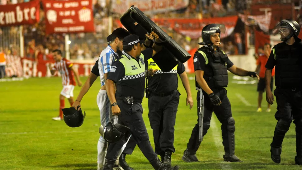 EL PEOR FINAL. Un jugador de Atlético deja la cancha escoltado por la Policía. iNÉS QUINTEROS ORIO / LA GACETA