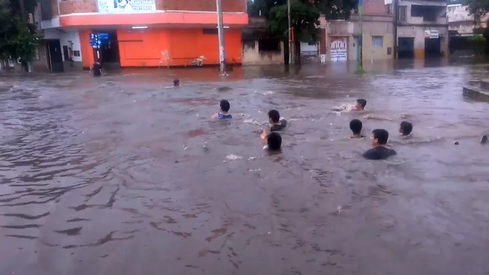 COMO EN UNA PILETA. Chicos de la zona se dejaron llevar por la correntada que se formó en calle Bolivia. CAPTURA DE VIDEO