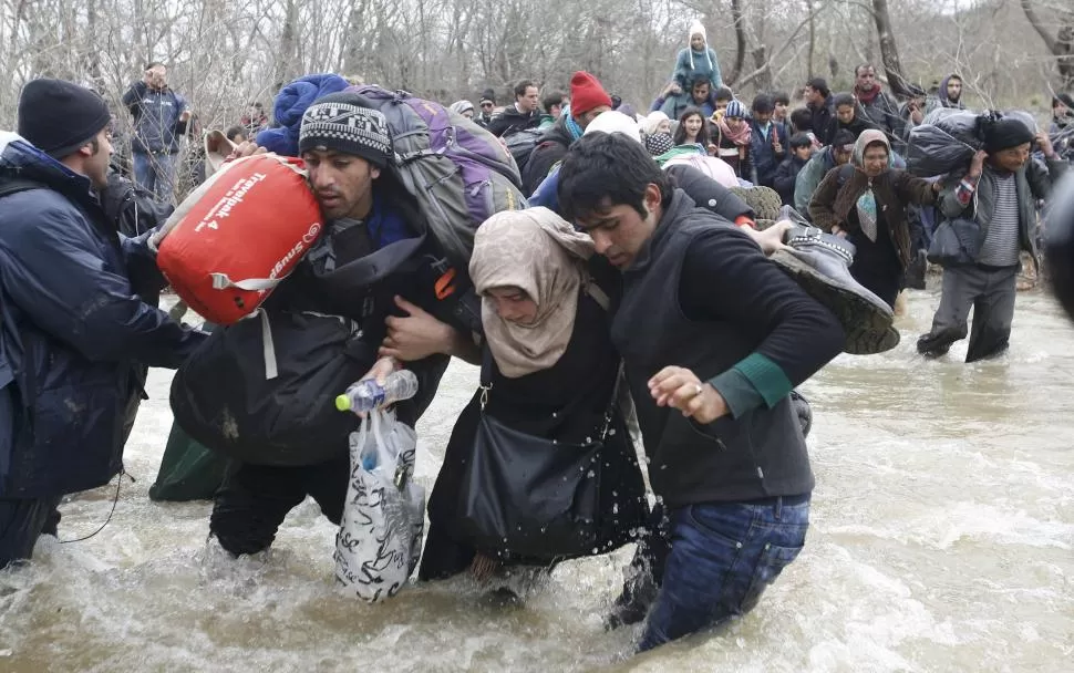 VIDAS EN PELIGRO. Migrantes y voluntarios de ONG los ayudaron a cruzar las bravas aguas del río Suba Reka. reuters 