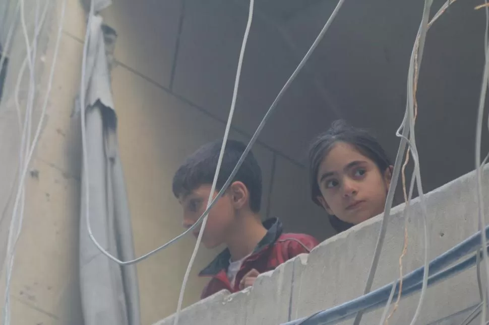 ATENTOS. Dos niños miran los combates que se desarrollan en Alepo. reuters