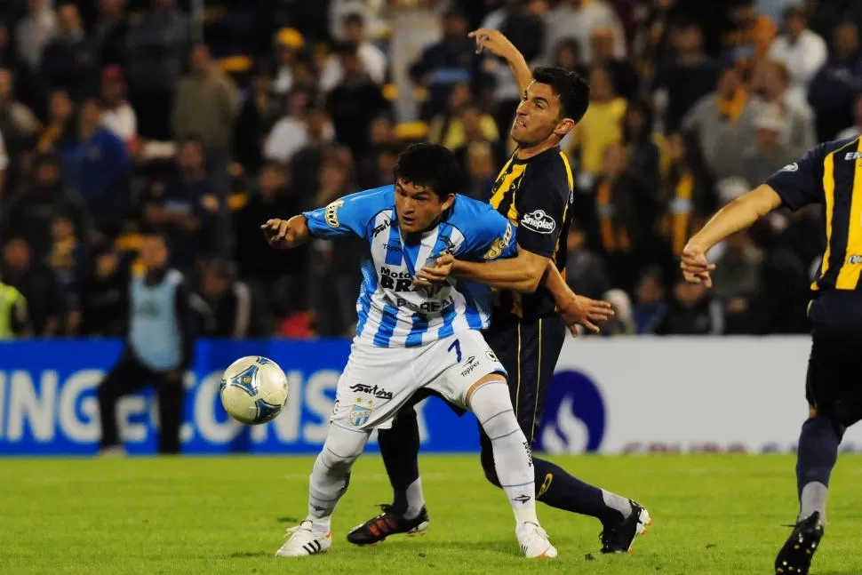 LUCHA. “Pulguita” aguanta la pelota ante Franco Peppino, en septiembre de 2012, la última vez que Atlético jugó en Rosario. foto de JAVIER ESCOBAR (archivo)