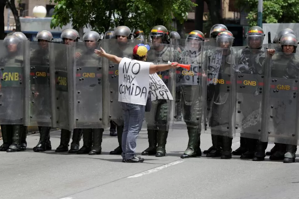 PIDIÓ POR LA PAZ. Un manifestante se paró ayer frente a las fuerzas de seguridad para clamar ayuda por la crisis alimentaria que sufre el pueblo. reuters 
