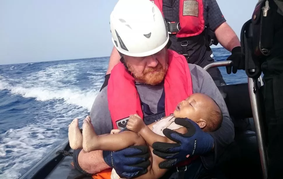 OTRA VIDA TRUNCADA. Un rescatista alemán sostiene en sus brazos a un bebé libio que sacó de las aguas. reuters