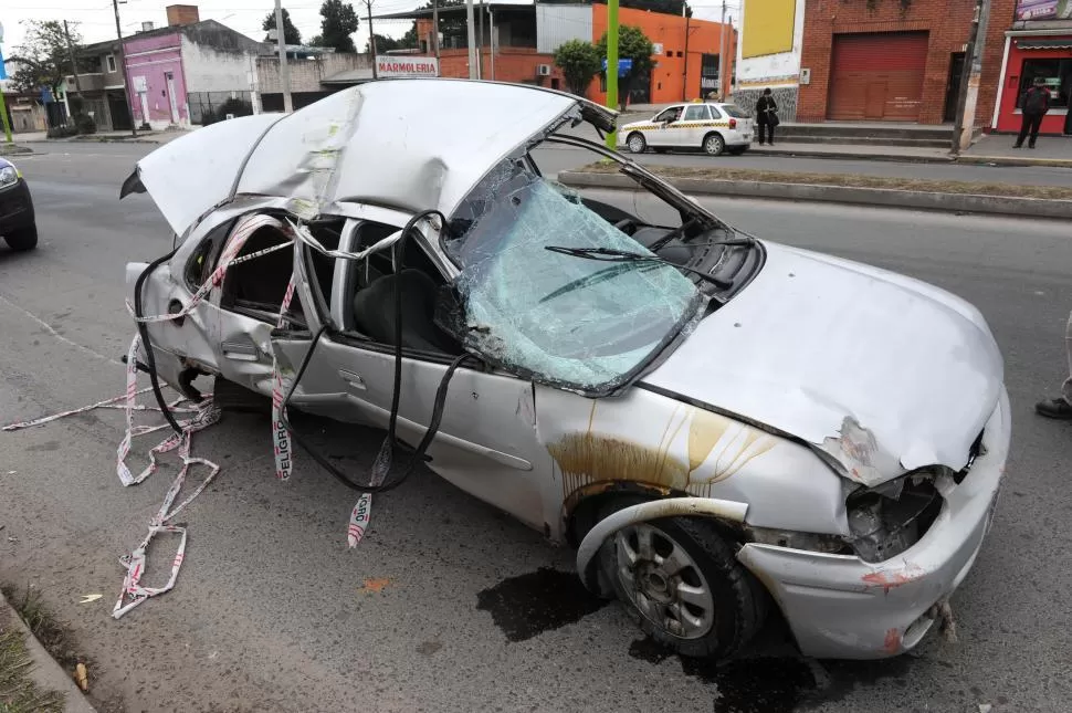 VUELCO MORTAL. El auto trepó la platabanda, chocó con un poste y volcó.