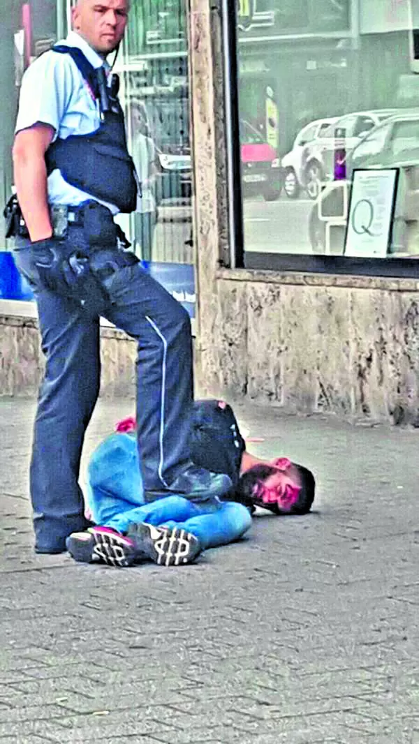 EL ATACANTE. Un policía mantiene en el piso al asesino, mientras espera para trasladarlo a una comisaría. twitter / @UKPegida