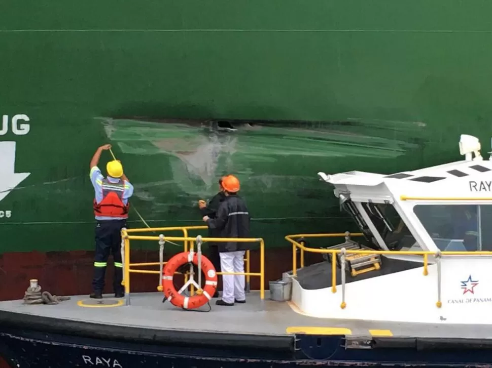 ASÍ QUEDÓ EL XIN FEI ZHOU. Empleados del Canal reparan la abolladura que sufrió el buque carguero chino al pasar por el nuevo sistema de esclusas.  