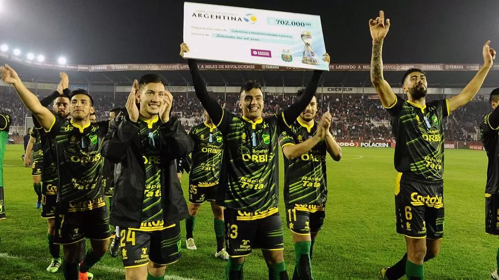 EL PREMIO. Los jugadores del Halcón celebran con el cheque de $720.000 que se llevaron. TELAM
