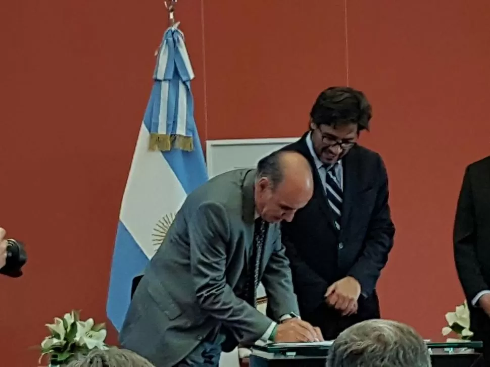 EN LA ROSADA. Jiménez firma el convenio, ante la mirada de Garavano. 
