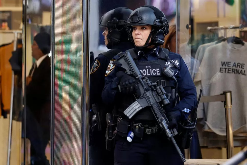 EQUIPADA PARA TODO. Una oficial de la Policía de Nueva York se mantiene vigilante en la puerta de un negocio. fotos reuters 