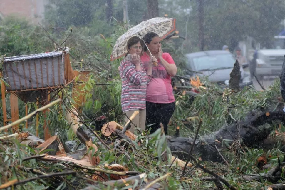 EL PEOR ESCENARIO. Dos mujeres lloran y observan el lugar de la tragedia; intentan cubrirse de la lluvia con un pequeño paraguas. LA GACETA / FOTOS DE ANALÍA JARAMILLO.-