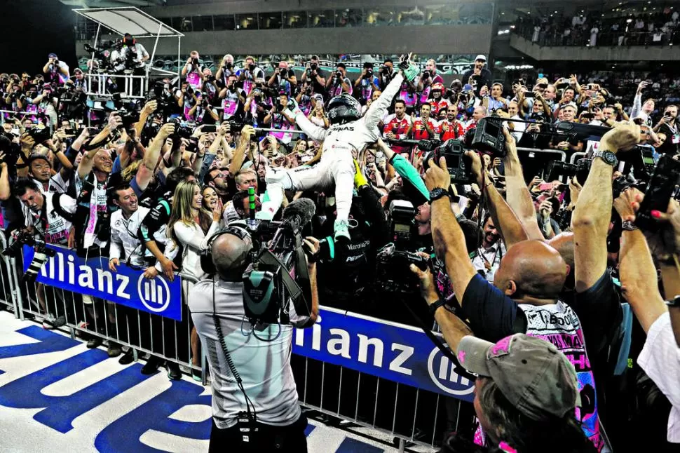 SE SACÓ LA ESPÍNA. El alemán Nico Rosberg festeja con la mirada al cielo, sostenido por los manos y brazos de los auxiliares del equipo Mercedes.La tensión por la definición ya era recuerdo. fotos de prensa mercedes benz / corsa