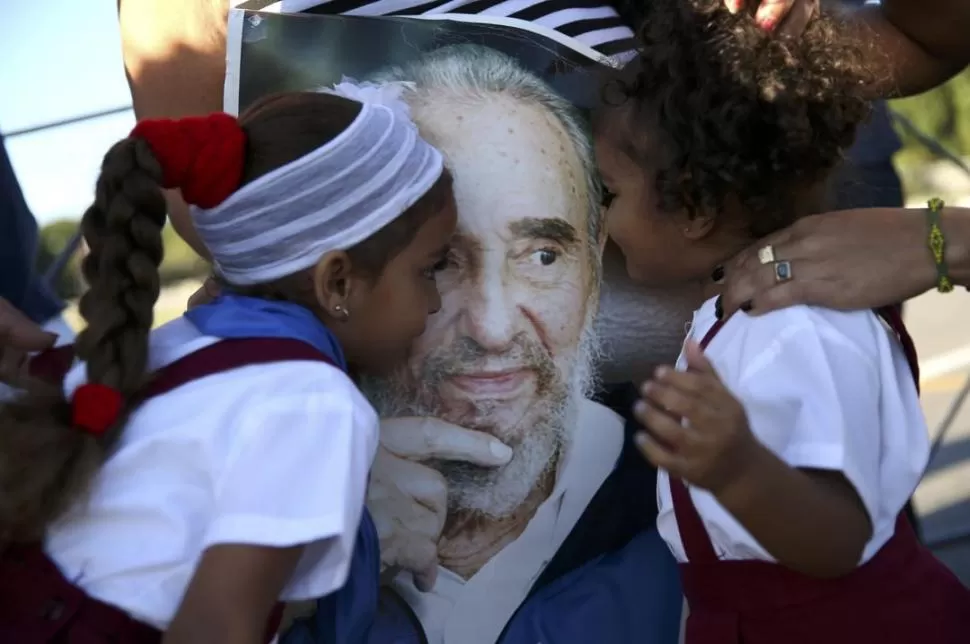HEREDERAS. Dos niñas cubanas besan un afiche con la imagen de Fidel. Reuters
