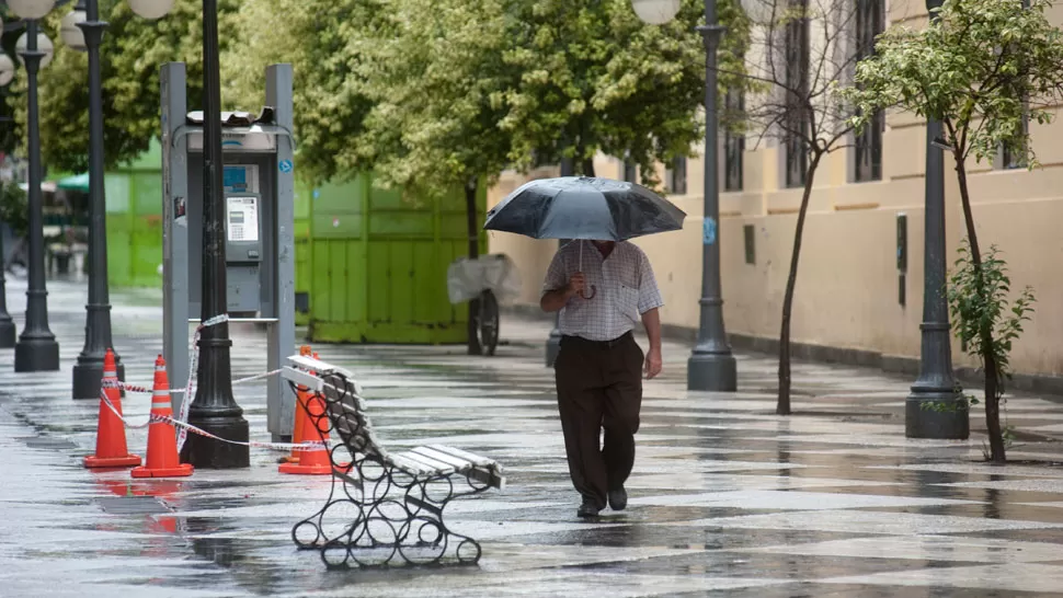 MICROCENTRO VACÍO. Un hombre camina por Muñecas al 200 bajo la lluvia. ARCHIVO