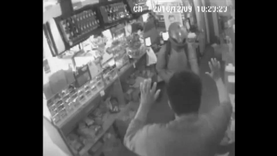 AMENAZAS. Uno de los ladrones apunta con un arma a un empleado. imagen captura de video