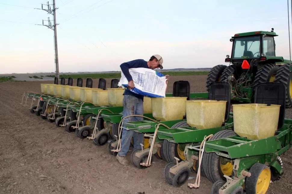 MANOS A LA OBRA. La imagen muestra al operario de una máquina sembradora, cargando los depósitos de semilla antes de continuar con su tarea a campo. 