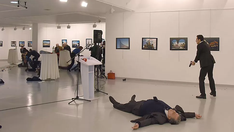 TREMENDO. El embajador está en el suelo y el atacante empuña su arma mientras los asistentes se ocultan detrás de mesas y sillas. FOTO TOMADA DE INFOBAE.COM