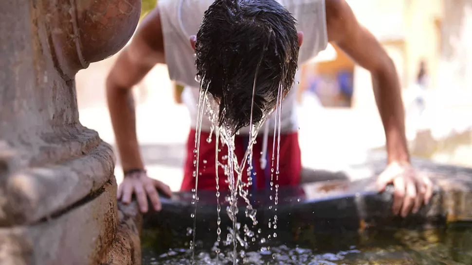 EN BUSCA DE ALIVIO. Un chico se moja la cabeza en una fuente. LA GACETA / ARCHIVO
