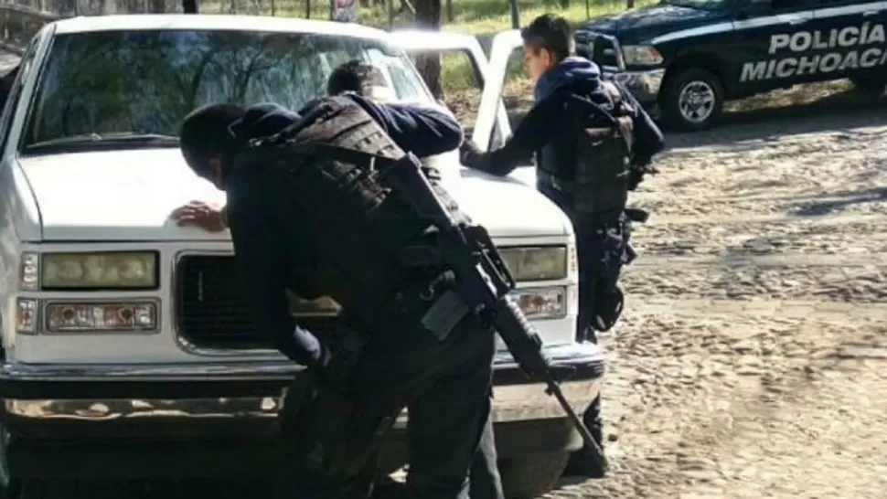 REQUISA. Policías revisan a todas las personas en las inmediaciones del macabro hallazgo, en Jiquilpan, Michoacán. FOTO TOMADA DE PROCESO.COM.MX
