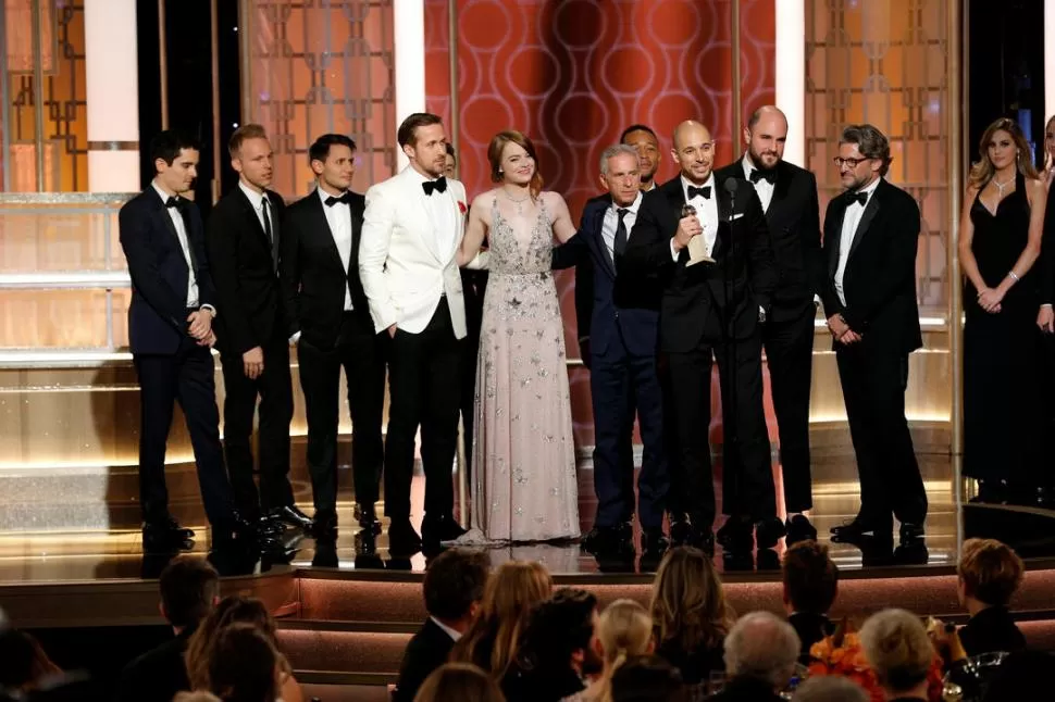 TODOS. Chazelle (primero a la izquierda), Gosling (de blanco) y Stone (al centro) subieron juntos al escenario para recibir el premio. 