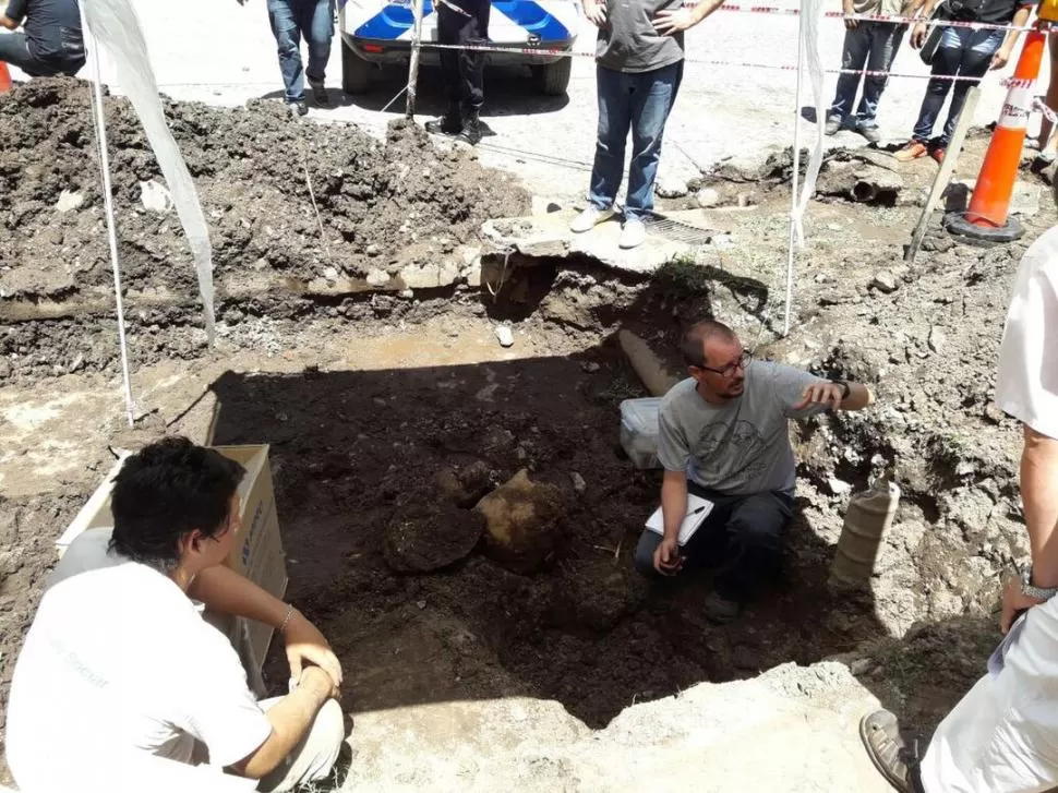 RESCATE. Los arqueólogos excavaron en la vereda donde se encontró el material para extraer la urna y los huesos y para buscar más alrededor. Municipalidad de Tafí Viejo