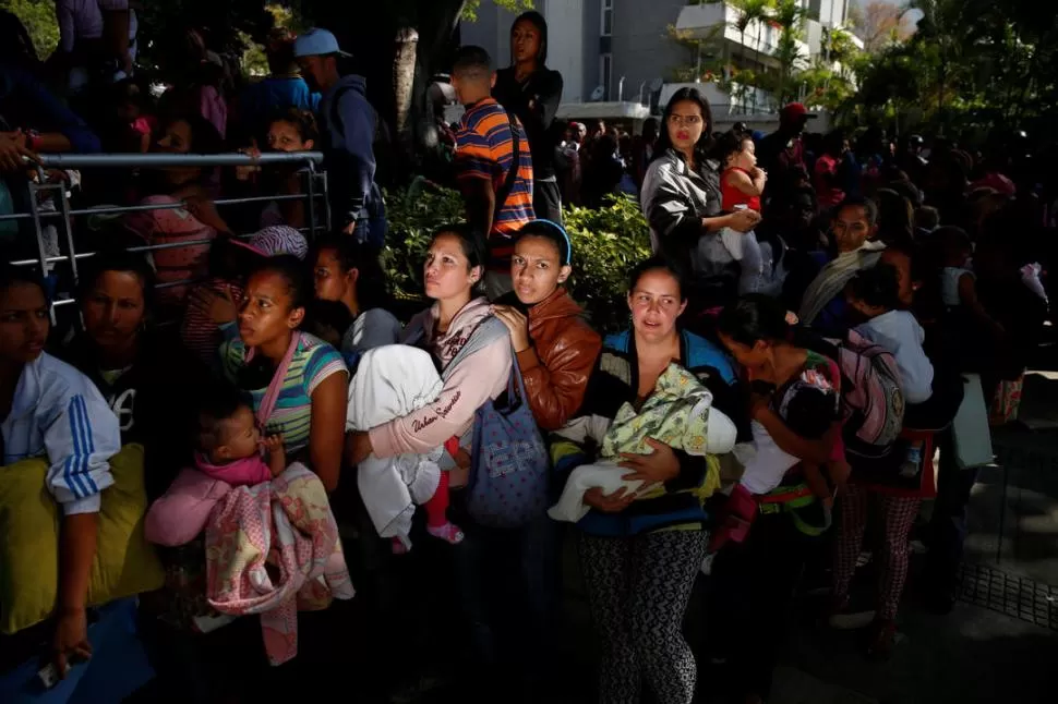 EN CARACAS. Mujeres con sus bebés en brazos esperan en una farmacia. reuters 
