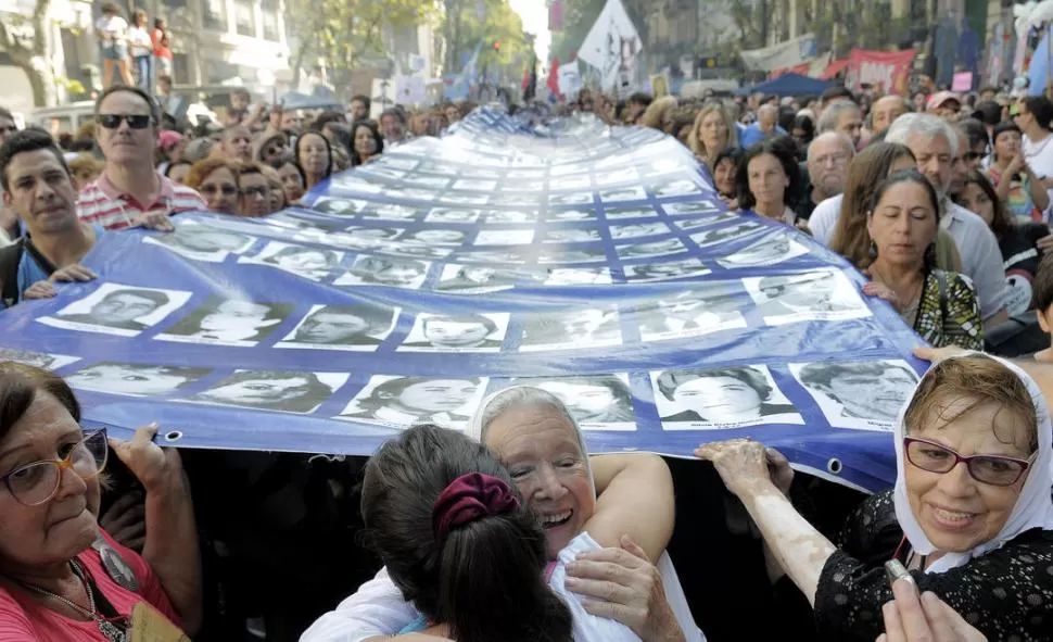 EN LA PLAZA. Nora Cortiñas (centro), de Madres Línea Fundadora, se abraza en el acto mientras marchaba junto a una bandera con fotos de desaparecidos. dyn