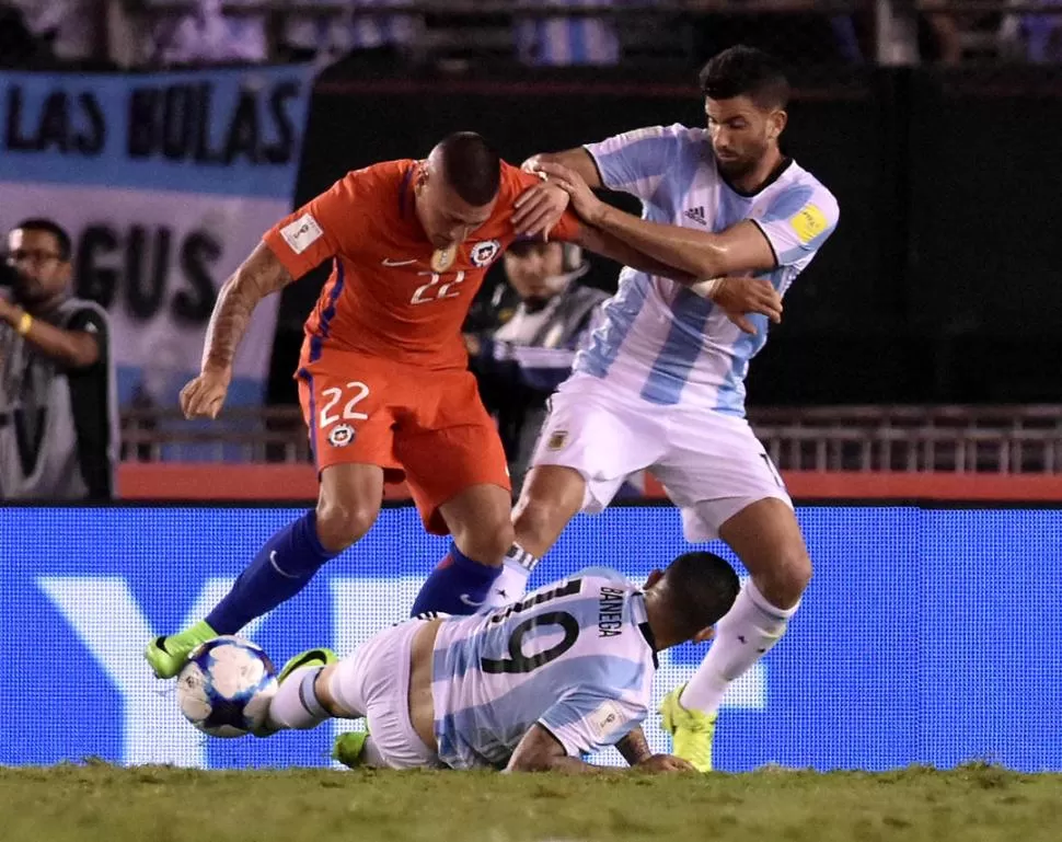 DESESPERADOS. Musacchio y Banega intentan frenar como sea a Castillo, de Chile. En el partido, Argentina nunca le encontró la vuelta a su rival.  dyn