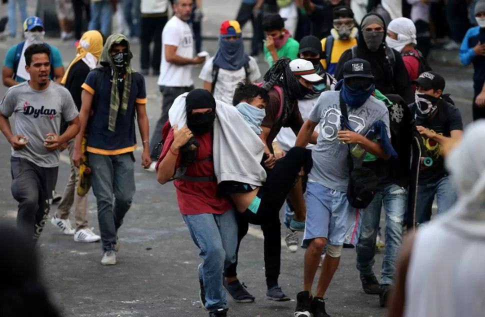 EL SALDO. Un manifestante herido es retirado de uno de los numerosos enfrentamientos con la Policía. reuters 