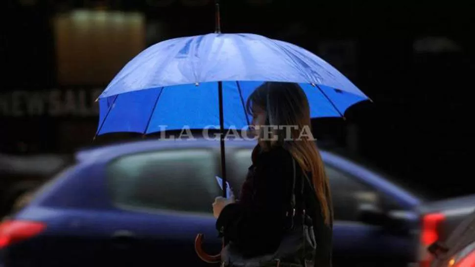 LLUVIA. Una mujer camina por el centro tucumana equipada con un paraguas; vos no te lo olvides si estás por salir. ARCHIVO