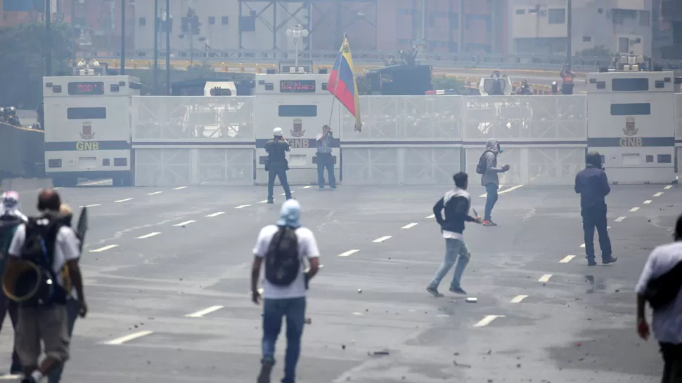 GASES LACRIMÓGENOS. Entre la nube de gases se divisa a algunos manifestantes y a la Policía, parapetada detrás de las vallas. REUTERS