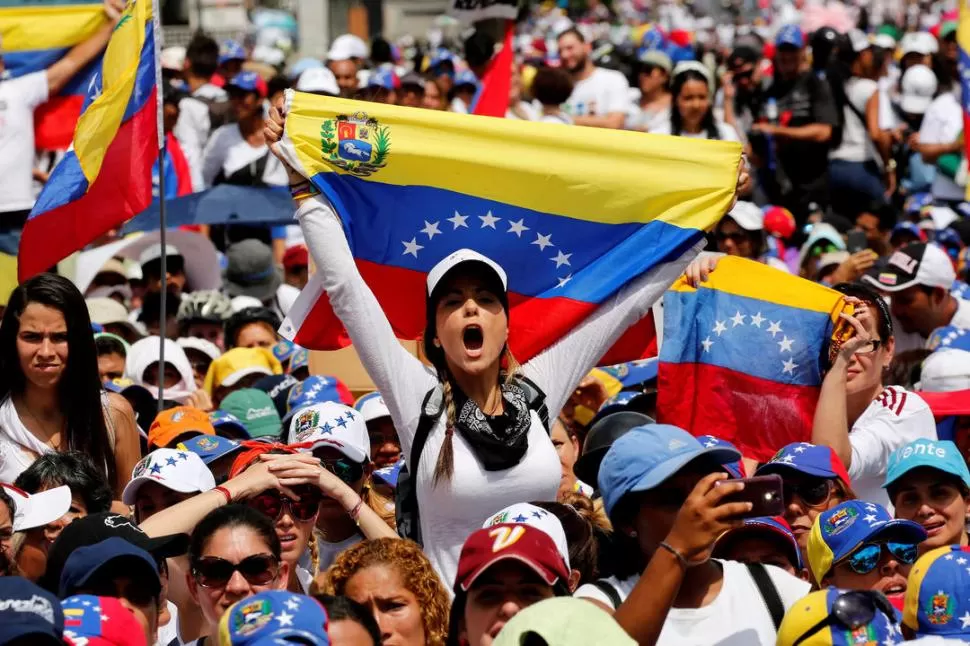 FLAMEANDO LA INDIGNACIÓN. Una venezolana grita consignas mientras sostiene una bandera de su país, durante la marcha que el pasado sábado 6 realizaron las mujeres en Caracas para protestar contra el gobierno de Nicolás Maduro. 