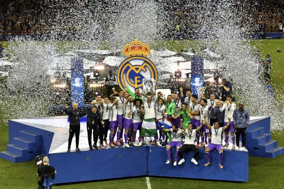 ALEGRÍA TOTAL. Embanderado con los colores de España, el capitán Sergio Ramos levanta la duodécima “Champions” mientras sus compañeros deliran en el podio. reuters